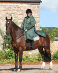 EQUIDRY women's long waterproof horse riding coat in black forest green/cream modelled by rider out hacking on horse showing storm skirts 