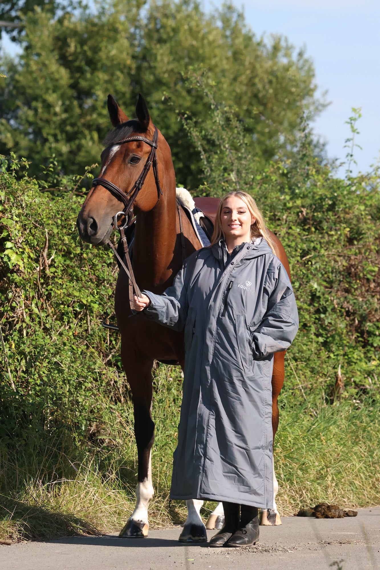 EQUIDRY women's long waterproof horse riding coat in charcoal/grey modelled by rider with horse