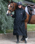 EQUIDRY women's long waterproof horse riding coat in black/peacock pink shown by rider with horse