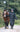 EQUIDRY women's long waterproof horse riding coat in black/turquoise modelled by rider walking with horse 