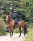 EQUIDRY women's long waterproof horse riding coat in black/peacock pink shown by rider out hacking on horse