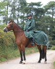 EQUIDRY women's long waterproof horse riding coat in black forest green/green modelled by rider hacking on horse