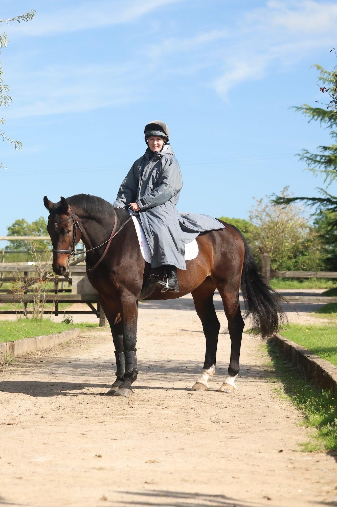 EQUIDRY women's long waterproof horse riding coat in charcoal/grey modelled by rider on horse