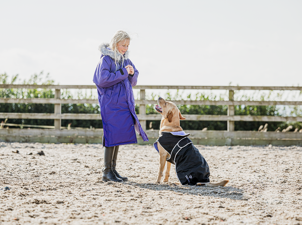 EQUIDRY Evolution Lux children's Warm Waterproof Winter Horse Riding Coat Thick Fleece Lining with Faux Fur Trim Hood being shown in purple by girl playing with dog in matching dog coat