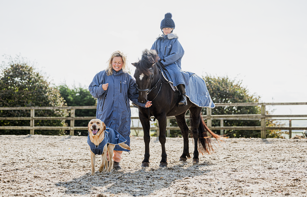 EQUIDRY women's long waterproof horse riding coat in steel blue/charcoal group family shot with horse and dog in matching rug and coat