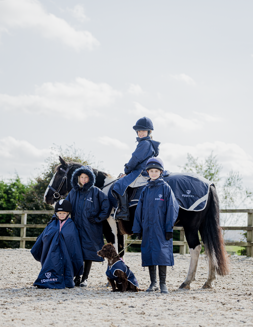 EQUIDRY waterproof horse riding raincoat thin fleece pro ride reflective in navy rider on back of horse with group navy family shot