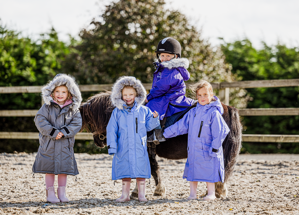 EQUIDRY Evolution Lux children's Warm Waterproof Winter Horse Riding Coat Thick Fleece Lining with Faux Fur Trim Hood being shown in purple, sky blue, charcoal/pale pink with kids on horse 