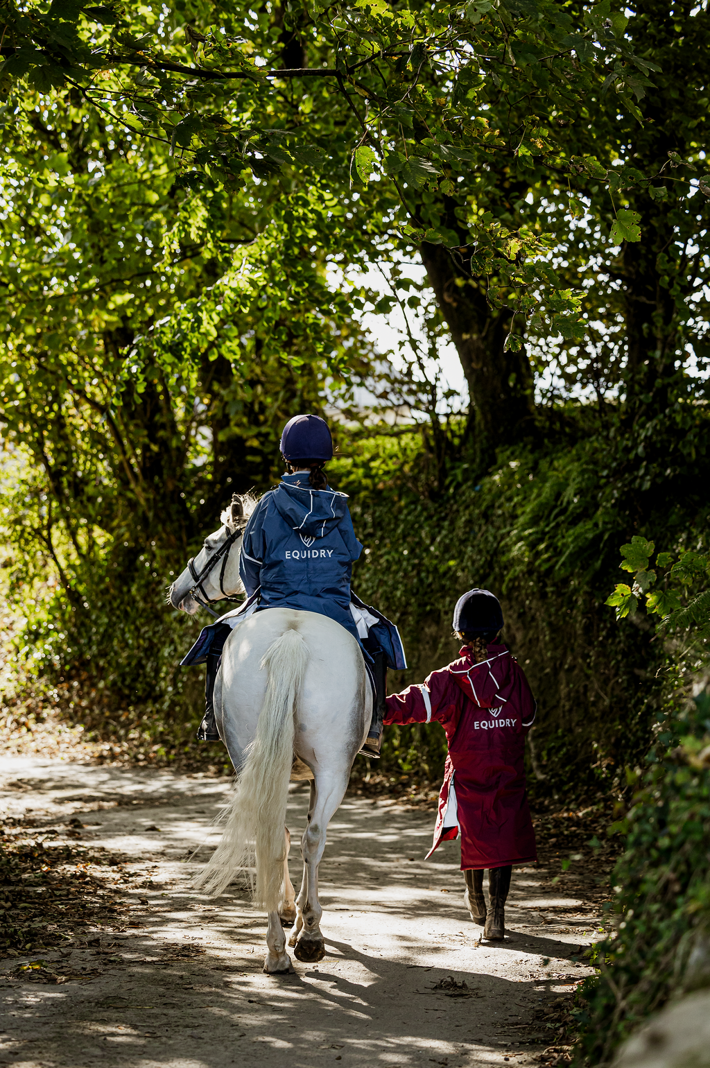 EQUIDRY waterproof horse riding raincoat thin fleece pro ride reflective kids plum and steel blue children's jackets rider on horse back view 