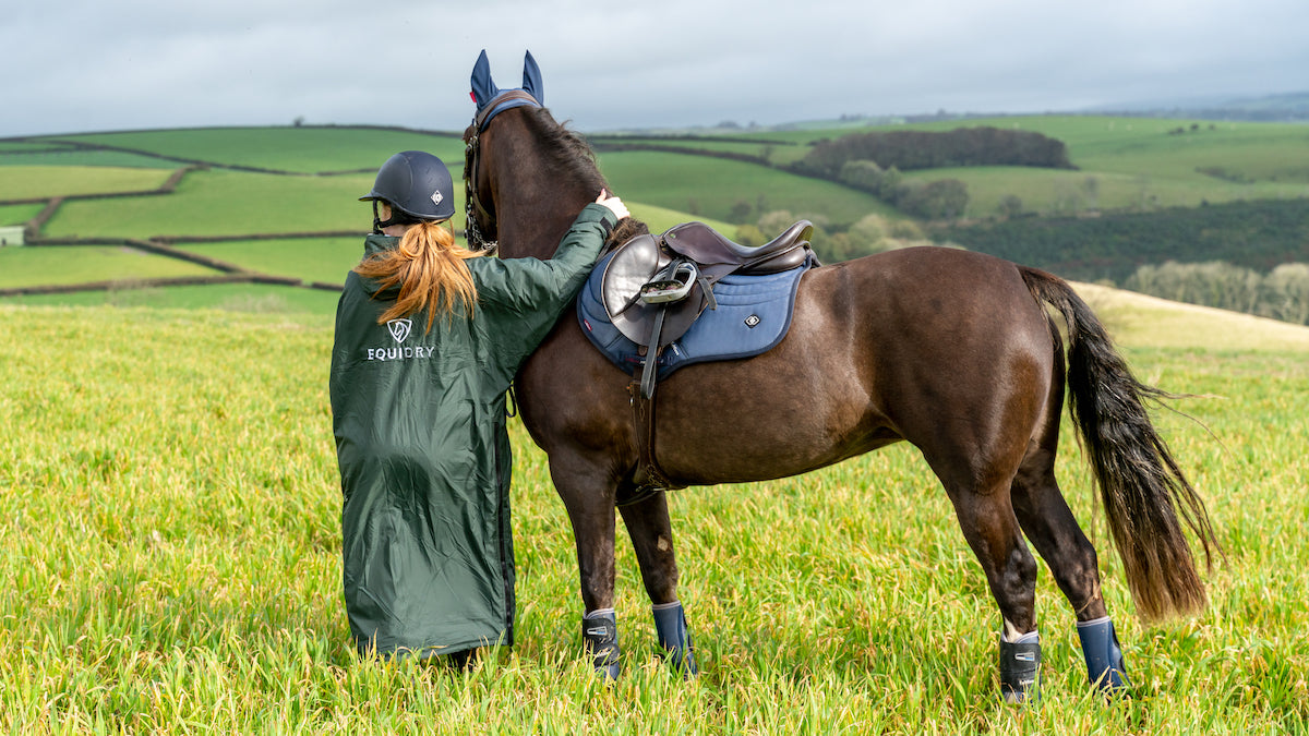 Grey EQUIDRY all rounder original oversized waterproof Horse Riding Coat modelled by rider with horse in a country field  