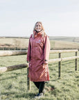 EQUIDRY chestnut equmac lightweight adjustable long riding coat modelled by lady walking in field 