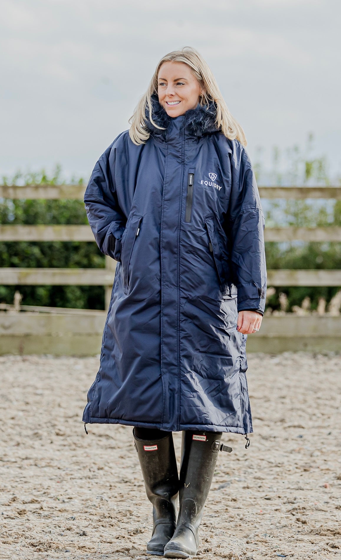 EQUIDRY Evolution Lux Women's Warm Waterproof Winter Horse Riding Coat Thick Fleece Lining with Faux Fur Trim Hood navy/cream front full view rider in arena 