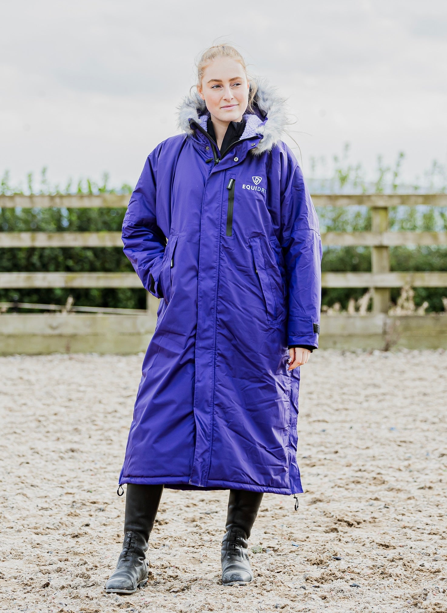 EQUIDRY Evolution Lux Women's Warm Waterproof Winter Horse Riding Coat Thick Fleece Lining with Faux Fur Trim Hood purple rider in arena full front view 