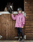 Shortie Child's Oversized Short Waterproof Riding Jacket Thin Fleece Lining Stowaway Hood in valerian worn by child with horse on yard