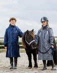 EQUIDRY waterproof horse riding raincoat thin fleece pro ride reflective in navy and charcoal/pale pink children's kids stood with shetland in arena 