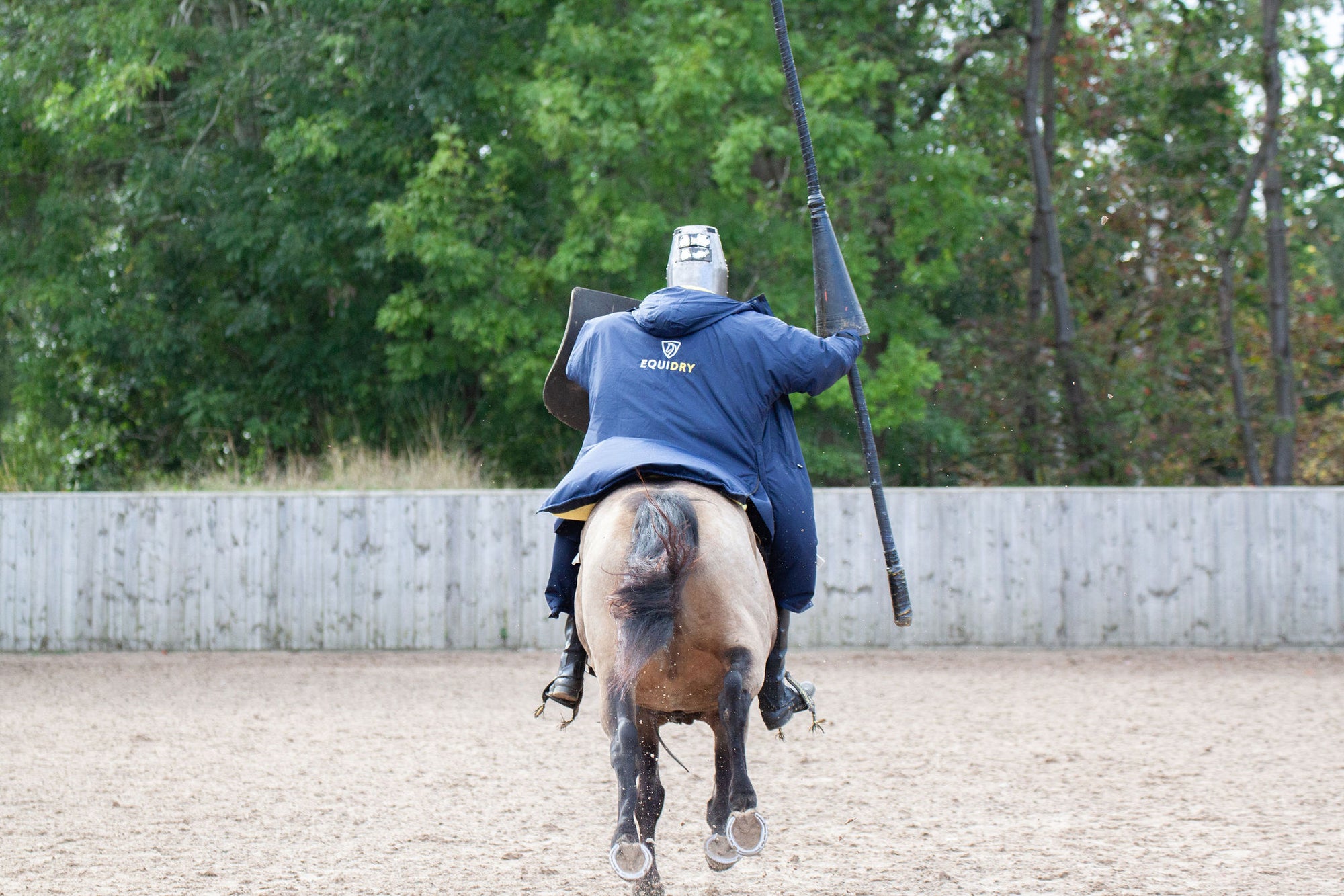 EQUIDRY men's long waterproof horse riding coat in navy/yellow worn by male stunt rider back of coat