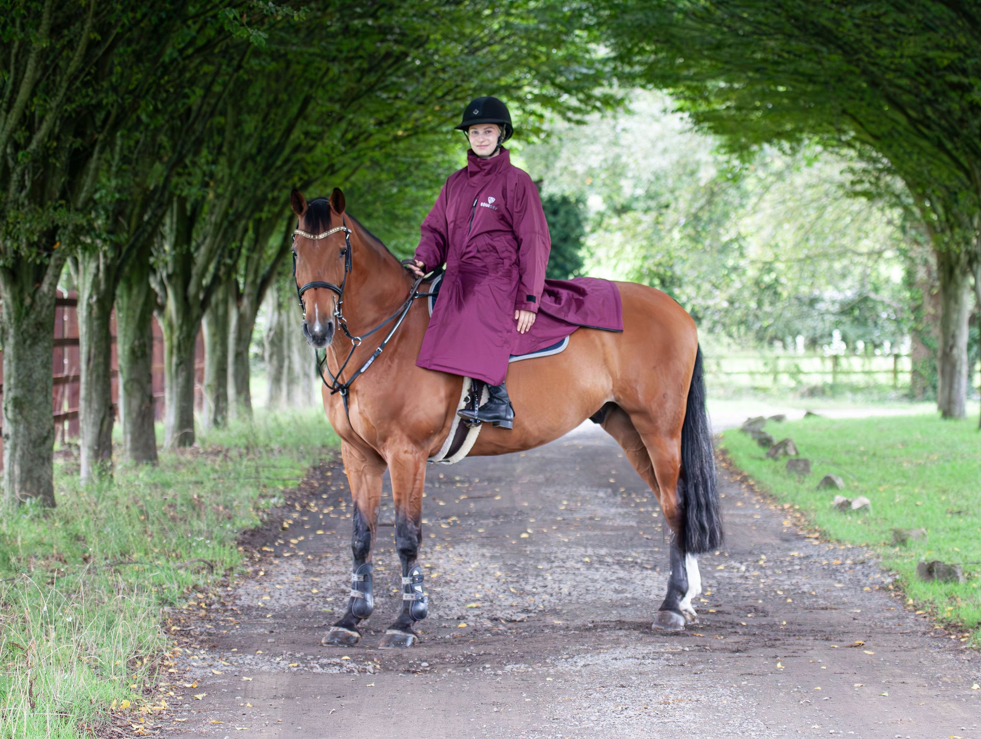 EQUIDRY women's thin fleece stowaway hood long waterproof horse riding coat in plum on horse