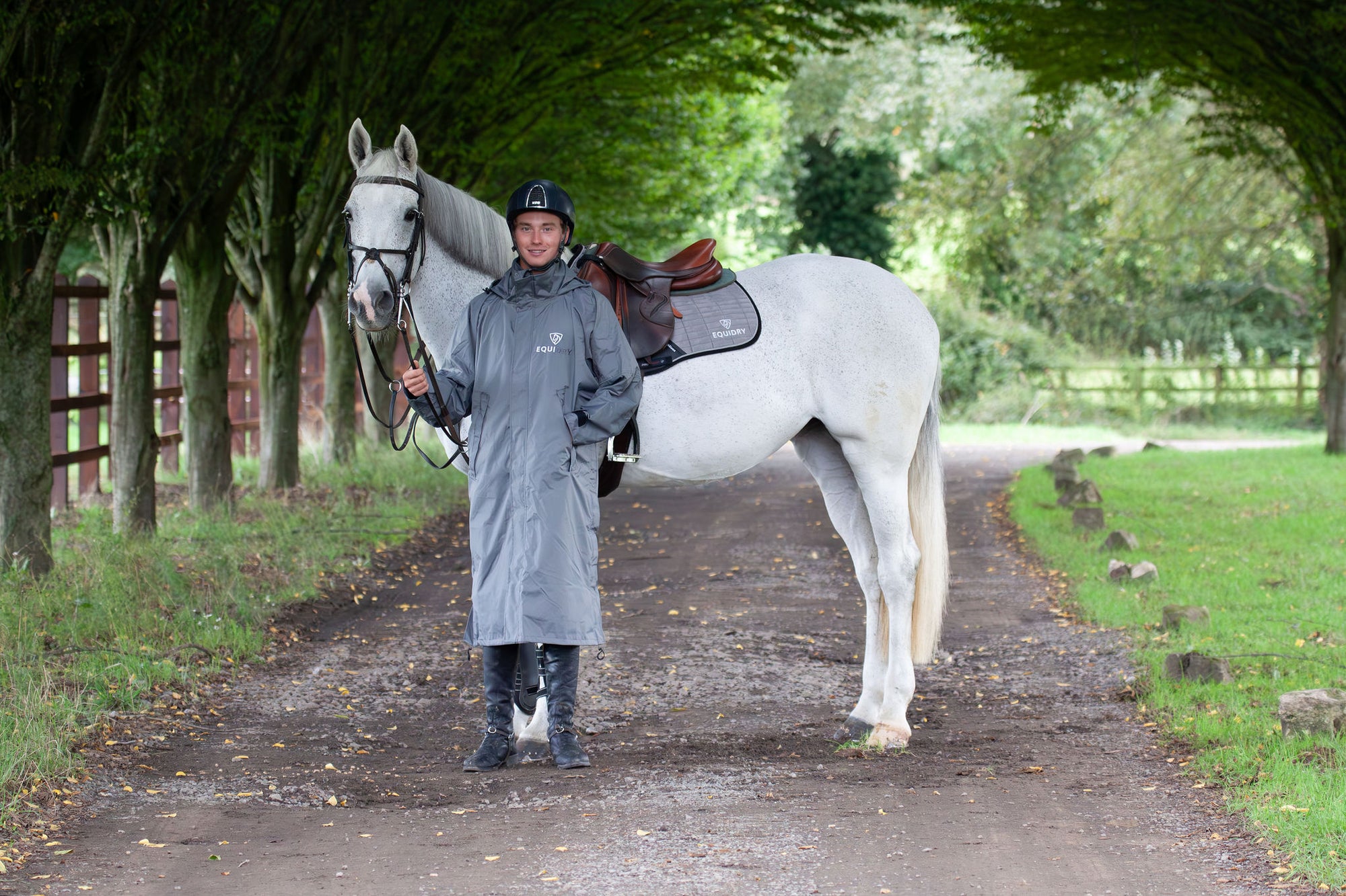 Evolution Equimac Men's Lightweight Waterproof Horse Riding Raincoat in charcoal modelled by male rider with horse