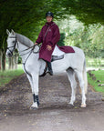 Evolution Reflective Men's Lightweight Waterproof Horse Riding Coat in plum worn by male rider on horse showing storm skirts 