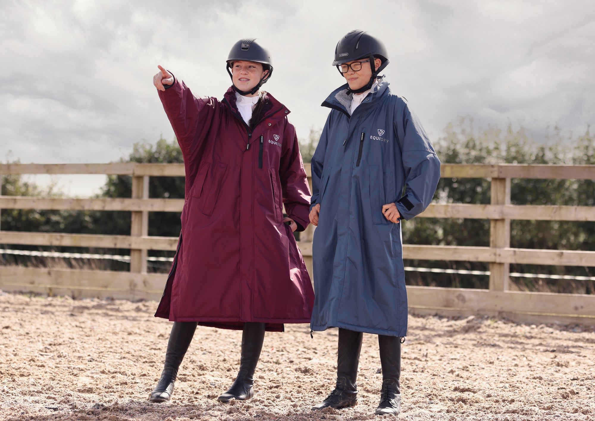 EQUIDRY Pro Ride Evolution Equestrian oversized waterproof Horse Riding Coat in Navy and plum modelled by rider&#39;s course walking a  jumping arena 