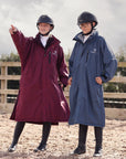 EQUIDRY Pro Ride Evolution Equestrian oversized waterproof Horse Riding Coat in Navy and plum modelled by rider's course walking a  jumping arena 