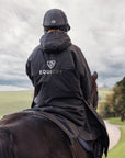 EQUIDRY women's long waterproof horse riding coat in black/olive modelled by rider out hacking horse